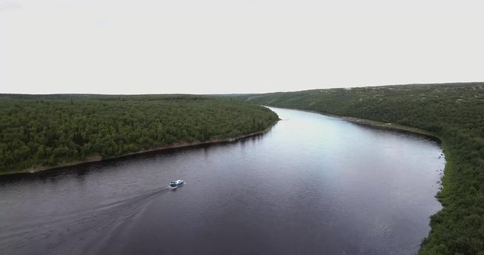 Following Boat with drone over a wide river in the untouched nature