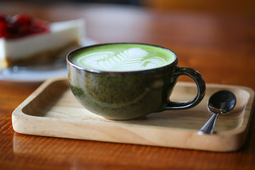 A cup of green tea latte on wooden table.