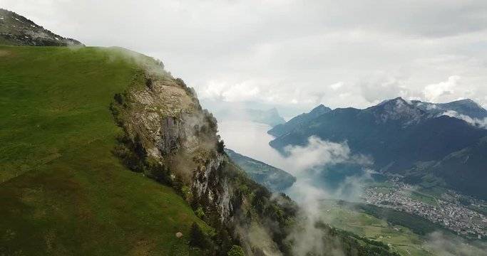 Sideways aerial pan shot of Lake Lucerne, Switzerland with fog and rocky cliff, on Fronalpstock.