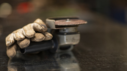 Obraz premium Manual electric sander, protective gloves, background blur and reflection on the table 