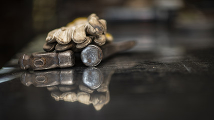 Iron hammer, protective gloves, background blur and reflection on the table 
