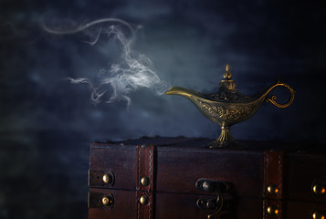Image of magical mysterious aladdin lamp with smoke over black background. Lamp of wishes.