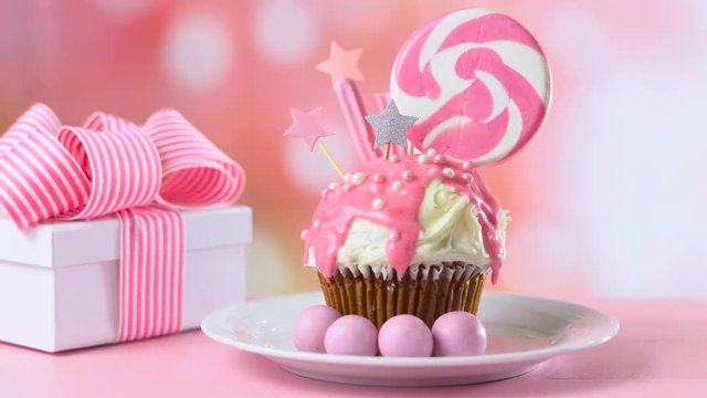 Pink theme colorful novelty cupcake decorated with candy and large heart shaped lollipop for children's or teen's birthday, Valentine's or Mother's Day celebrations.