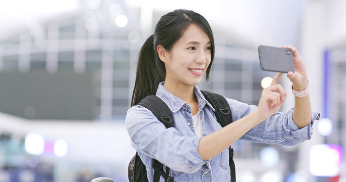 Woman taking photo by mobile phone in the airport