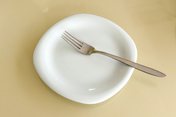 On the table is a white plate with a fork.