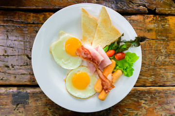 American breakfast with eggs, bacon, toast, ham, sausage, vegetable salad