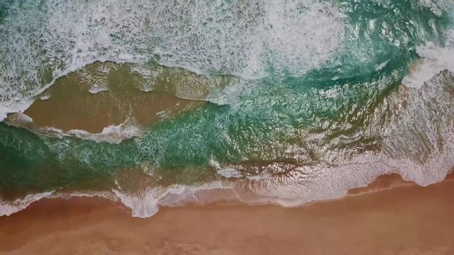 Aerial view of sand beach. Looping ocean texture, Top view sea waves slow motion, flying over tropical sandy beach and waves, Sunset beach seamles loop.
