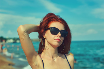 portrait of a young red-haired woman on the sea .Young girl lying on the beach