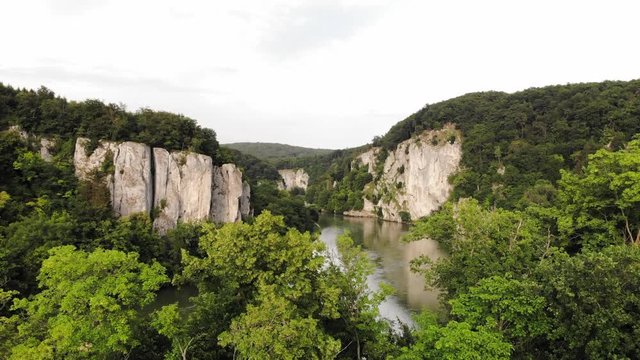 A slow rising drone shot from a distance of a beautiful bend in the Danube River near Kelheim in Germany.