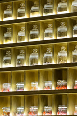 Tea and various spices in glass jars on shelves with lighting. Sale of tea in the store