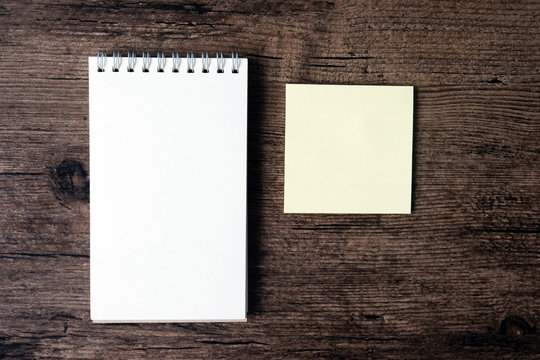 Top view image of blank notebook and empty sticky note paper on the wooden table..