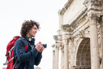 Handsome young tourist taking photos of Roman forum in Rome, Italy. Backpacker with his camera