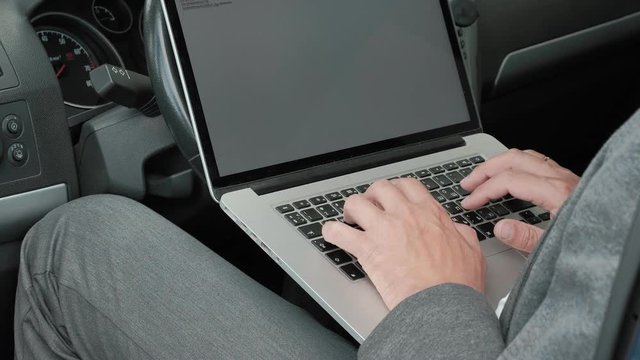 Mature businessman in car working on laptop