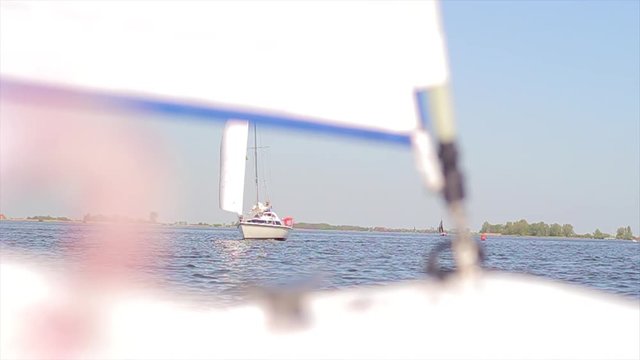 The front of a sailboat, switching focus between the sail and a passing boat.