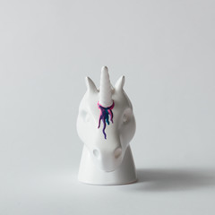 White painted unicorn head with colorful paint dripping on bright white background. Minimal art fantasy concept.