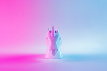 White painted unicorn head in bold pink and blue neon colors on gradient background. Minimal art...