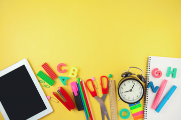 Back to school Accessories for school on a yellow background Pencils Plasticine letters Letters Alarm clock Briefcase Chalk Copy space Top view