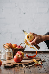 partial view of woman peeling apple with knife