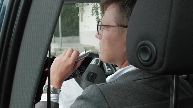 Mature businessman in car smokes a wape