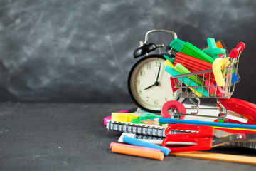 Back to school Accessories for school on a dark background Pencils Plasticine letters Letters Alarm clock Briefcase Chalk Copy space