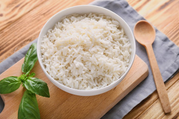 Bowl with boiled white rice on wooden table