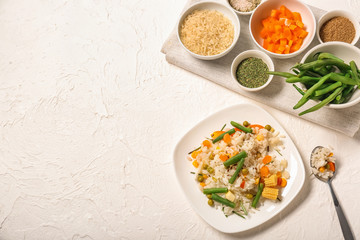 Plate with tasty boiled rice and vegetables on light background