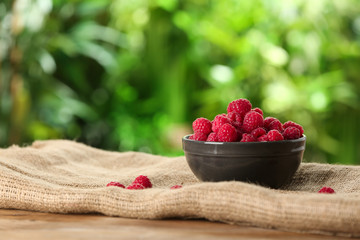 Bowl with fresh ripe raspberries on table outdoors