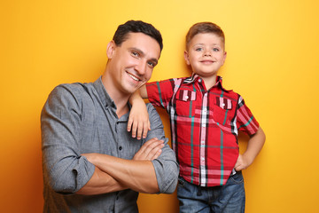 Little boy and his dad on color background