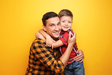 Little boy and his dad on color background