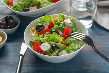 Fresh vegetable salad with black olives and feta cheese on color wooden table