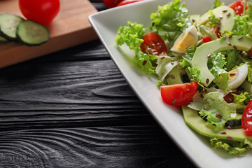 Plate with tasty vegetable salad on wooden table