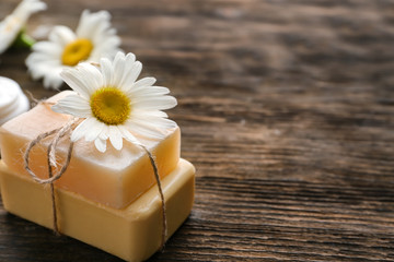 Obraz na płótnie Canvas Natural homemade soap with chamomile flower on wooden table