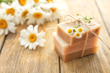 Fototapeta na wymiar Natural homemade soap with chamomile flowers on wooden table