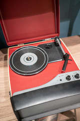 Red and black modern vinyl player on wooden table.