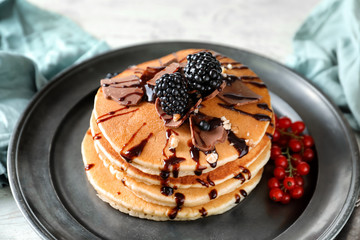 Tasty homemade pancakes with chocolate and blackberries on plate, closeup