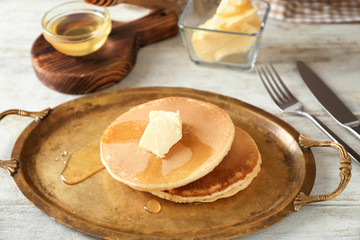 Tasty pancakes with butter and honey on tray