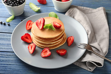 Plate with tasty homemade pancakes and strawberries on wooden table