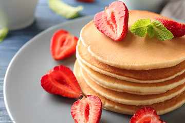 Tasty homemade pancakes with strawberries on plate, closeup