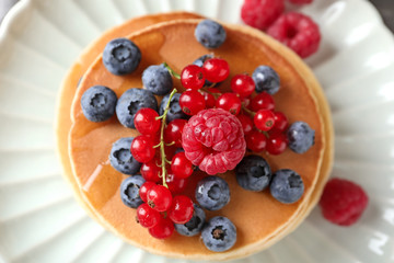 Tasty homemade pancakes with berries on plate, closeup