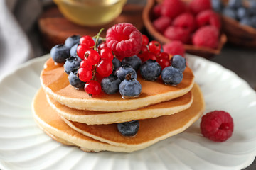 Tasty homemade pancakes with berries on plate, closeup