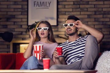 Young couple in 3d glasses watching movie on sofa at night