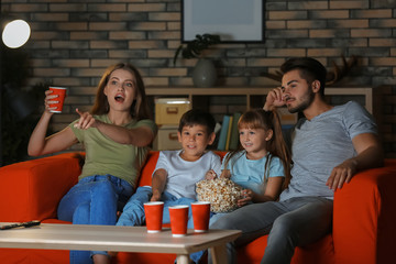 Family watching TV on sofa in evening