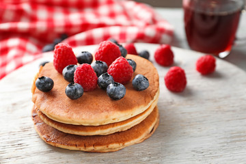 Stand with tasty pancakes and berries on table