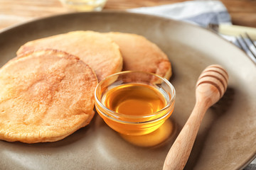 Tasty pancakes and honey on plate, closeup