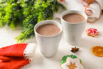 Cups of tasty cocoa and Christmas decor on light background