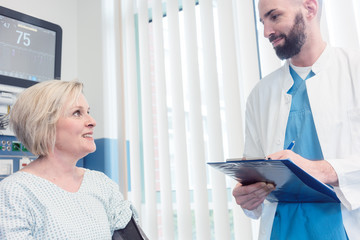 Doctor talking to patient in recovery room of hospital after awaking from treatment or surgery