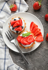 Plate with tasty tartlets on table