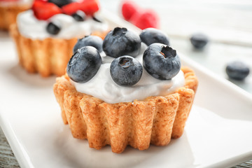 Tasty tartlets with berries on plate, closeup