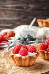 Tasty tartlets with raspberries on table