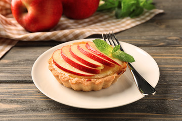 Plate with tasty tartlet on wooden table